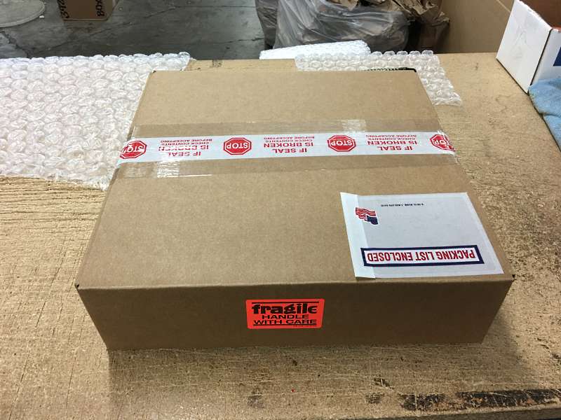 The box is sealed with multiple layers of packing tape and a red Fragile sticker is added to the top of the box.